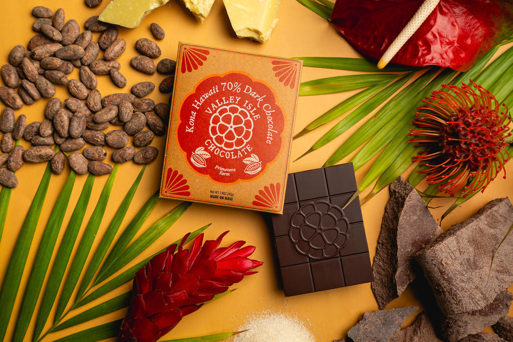 Box of Kona Valley Dark Chocolate with chocolate bars and coffee beans on a decorative surface.