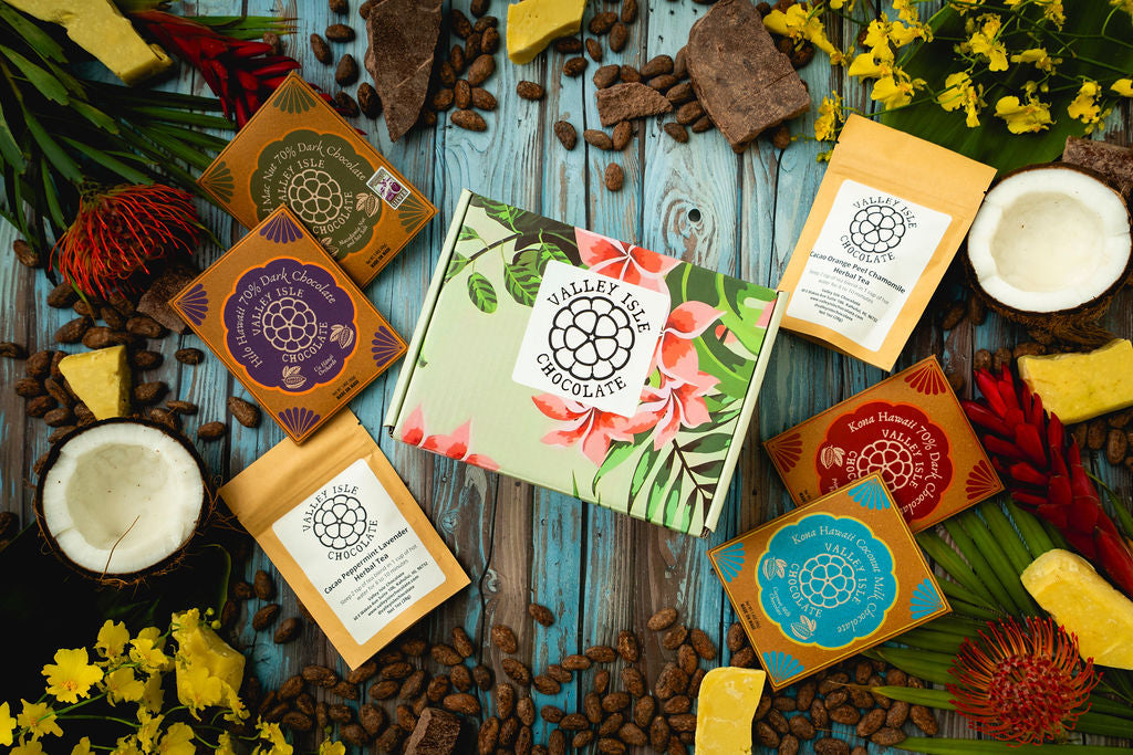 Assorted chocolate bars and packaging on a rustic wooden surface with flowers.