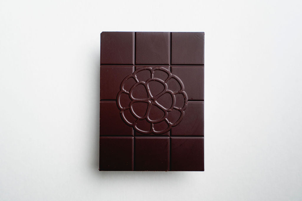 Dark chocolate bar with a decorative logo on a white background