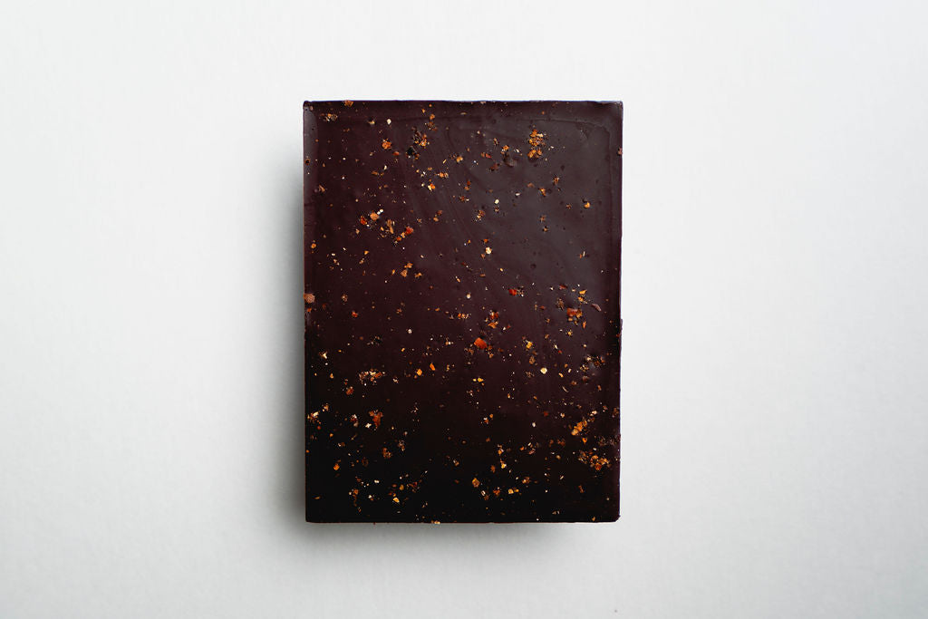 Dark chocolate bar with specks on a light gray background