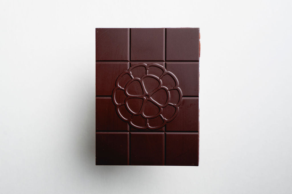 Dark chocolate bar with a decorative logo on a white background