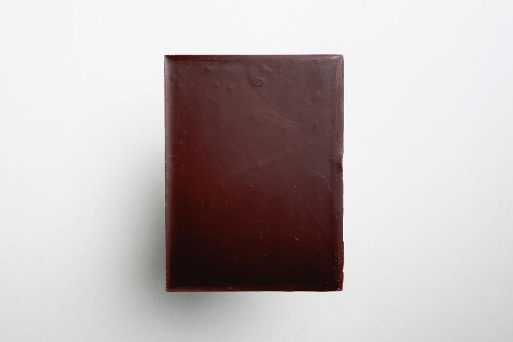 Dark brown rectangular bar of soap on a light gray background